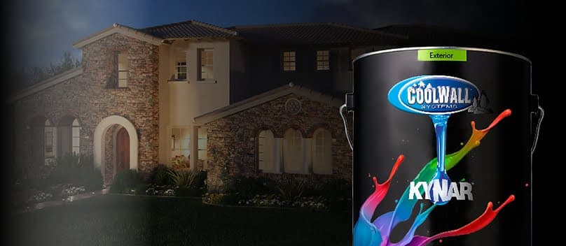 A large can of Coolwall by Kynar exterior paint with blue logo and colorful paint splashes, displayed against a nighttime backdrop of an illuminated two-story stone and stucco Mediterranean-style house.