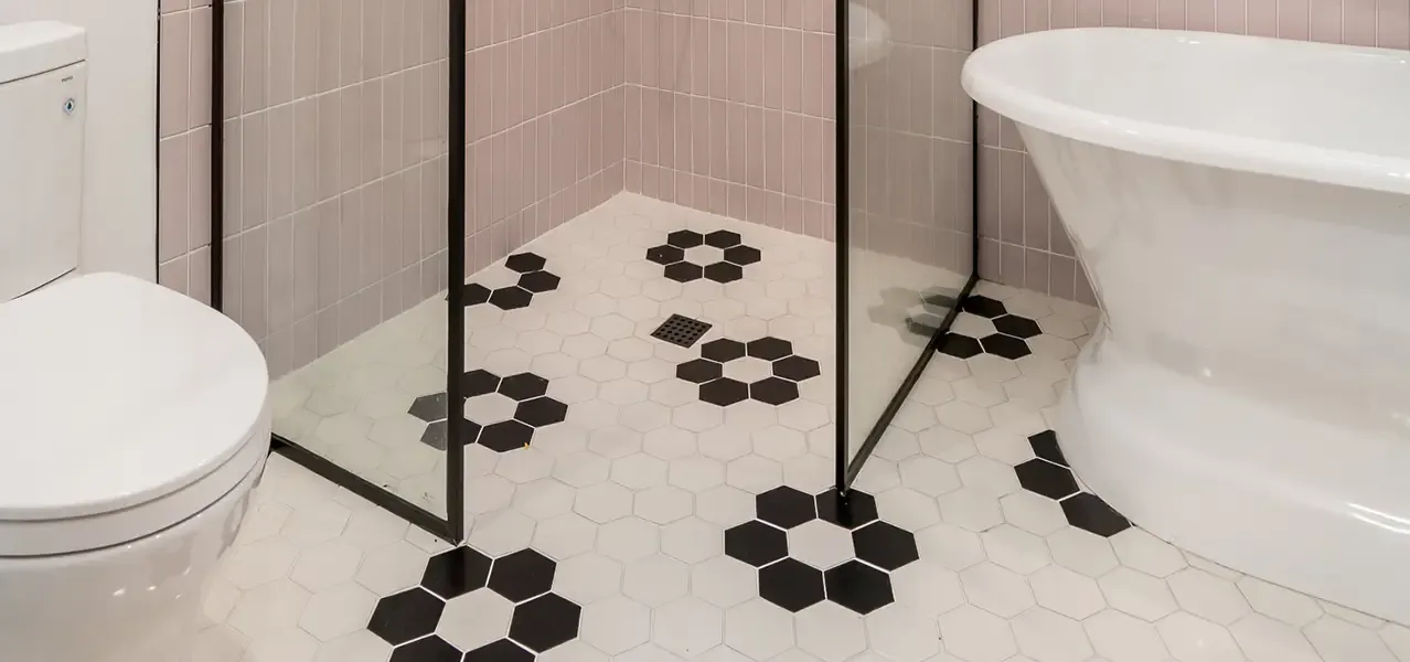 Modern bathroom with hexagonal floor tiles, freestanding tub, and glass shower enclosure.