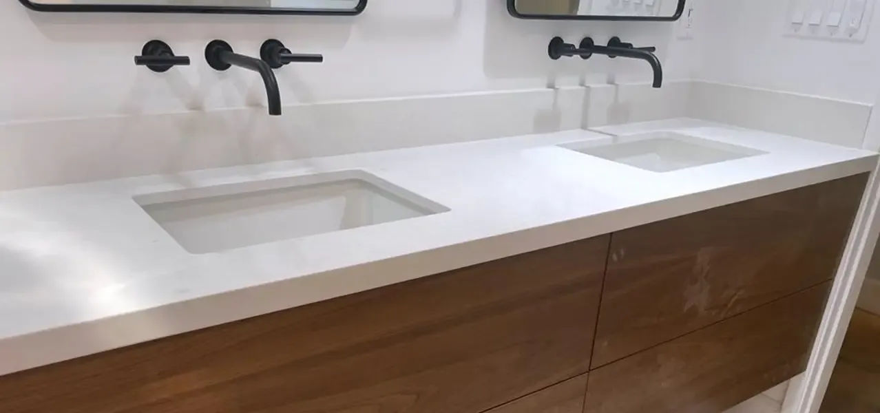 Modern bathroom with double sink, white countertop, wood vanity, and black fixtures.