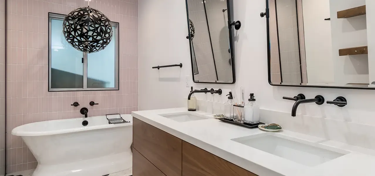 Modern bathroom with freestanding tub, double vanity, and black metal fixtures.