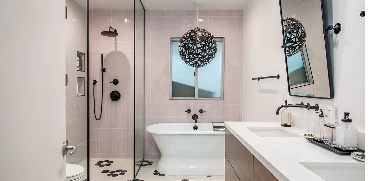 Modern bathroom with pink tiles, freestanding tub, and black/white hex floor.
