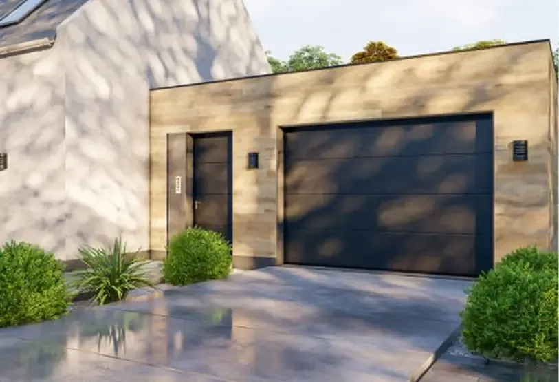 A modern residential building with a black garage door and light beige stone facade, featuring a side entrance and landscaping