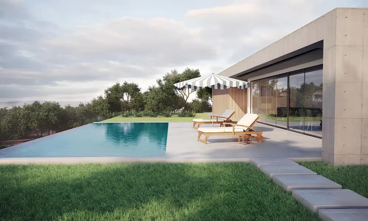 A serene infinity-edge pool with crystal-clear turquoise water surrounded by a light gray stone patio. Modern wooden lounge chairs with white cushions and a large blue-and-white striped umbrella sit on the deck against a backdrop of lush green hills and trees.